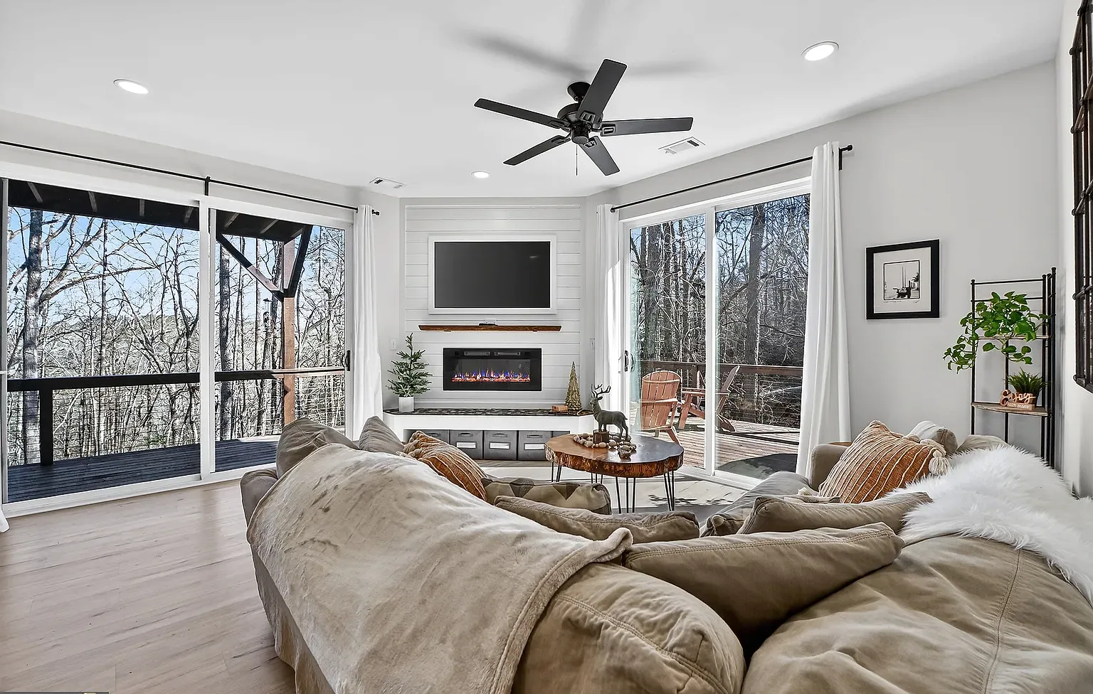 Bright living room with fireplace and wooded views